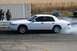 1997 Mercury Grand Marquis - A white sedan performs a burnout on a track, kicking up smoke as onlookers observe.