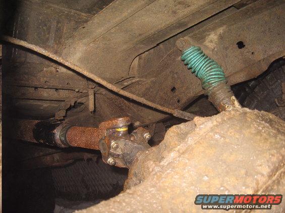 Close-up of a rusty rear axle and driveshaft with a green shock absorber boot