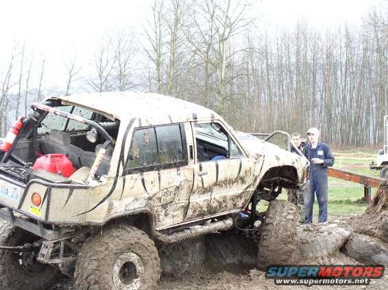 Mud-covered off-road SUV with large tires and a roll cage