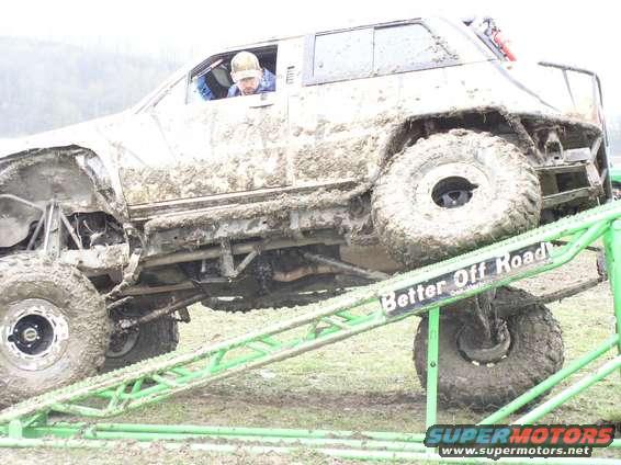 Mud-covered SUV with large tires on a green ramp