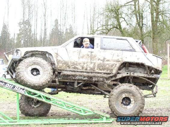 Mud-covered off-road vehicle on a ramp, side view