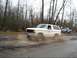 1980 Ford Bronco - White 1980 Ford Bronco navigating a muddy trail, with another truck visible behind it.