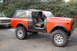 1994 Ford Bronco - This off-road SUV features a removable soft top and aggressive tires, parked next to another vehicle.