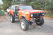 1994 Ford Bronco - International Harvester Scout II in orange, with a white pickup truck behind it.