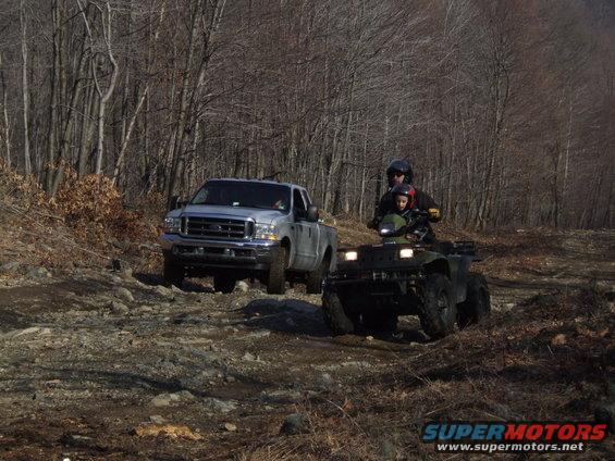 Pickup truck and ATV on a wooded trail