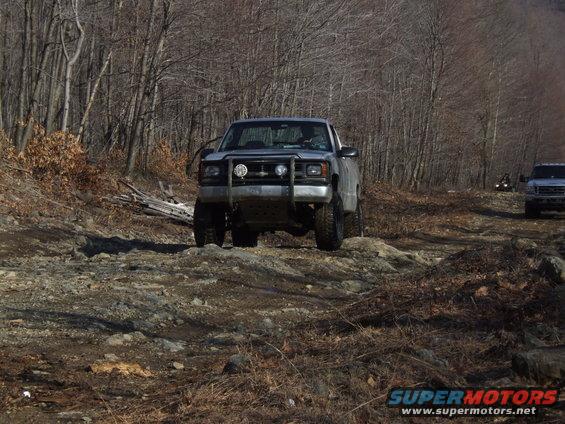 Silver pickup truck with bull bar and off-road tires on a rocky trail