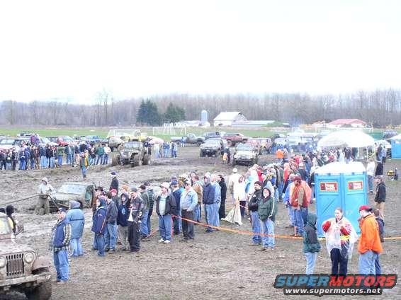 Muddy field with off-road vehicles and crowds gathered