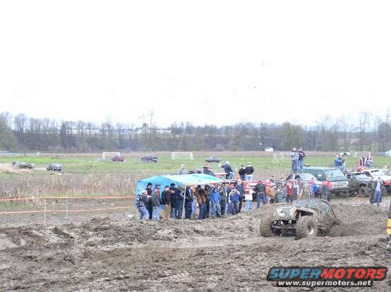 Off-road vehicles stuck in mud with spectators watching