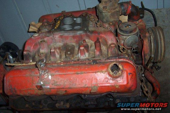 Red V8 engine with a chain attached, showing intake manifold and valve covers