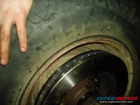 Close-up of a tire and brake rotor with a hand in the upper left corner