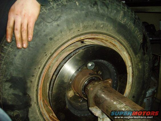 Wheel hub assembly with brake rotor and tire. A hand rests on the tire