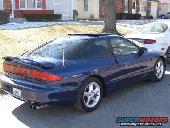 Blue 1995 Ford Probe GT coupe with a rear spoiler, dual exhaust, and a sunroof, parked on a residential street