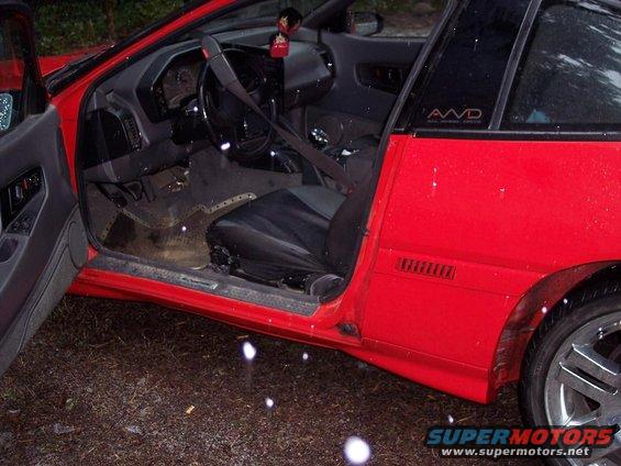 1991 Mitsubishi Eclipse interior, driver's side door open, showing dashboard, seats, and AWD badge on B-pillar