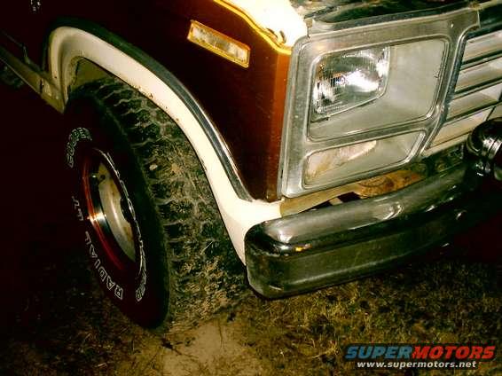 Front fender and tire of a 1980 Ford Bronco. Chrome bumper and grille visible