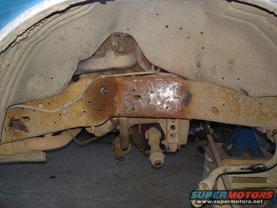 rusted vehicle frame and suspension parts, viewed from underneath