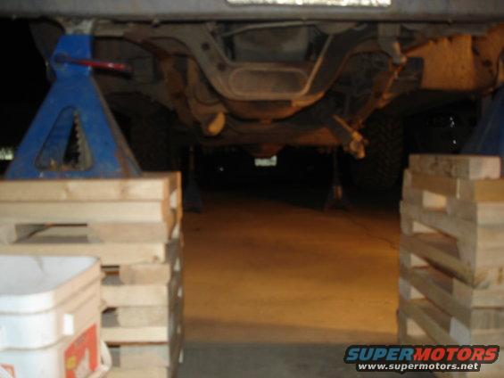 Undercarriage of vehicle on jack stands, showing suspension and exhaust components