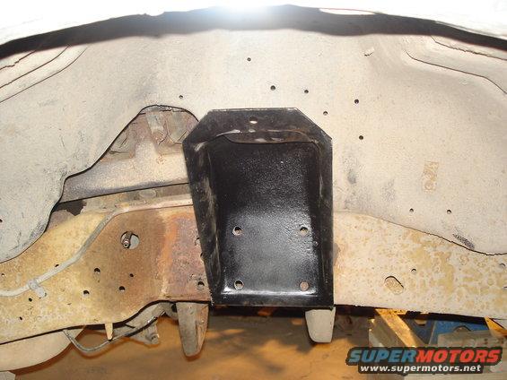 Black frame bracket mounted to rusty chassis