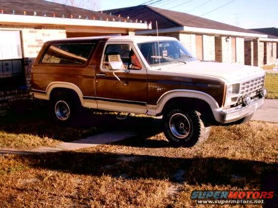 Brown and white Ford Bronco parked in front of a house