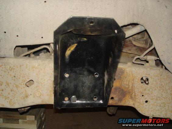 Close-up of a black metal bracket bolted to a rusty vehicle frame