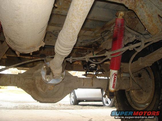 Undercarriage view showing differential, driveshaft, and Rancho shock absorber. Another vehicle is visible in the background