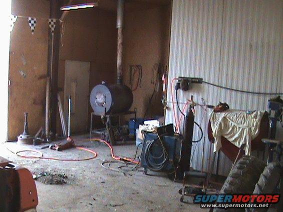 Workshop interior with a large cylindrical furnace, welding equipment, and a jack