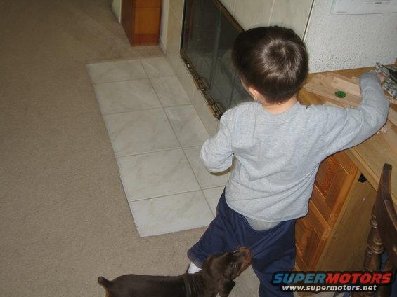 Child and dog in a room with tiled floor and wooden furniture
