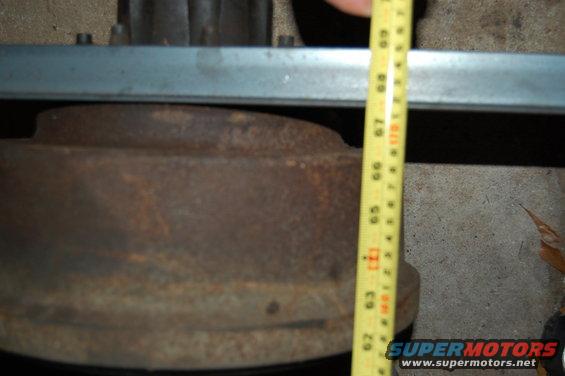 Close-up of a rusty brake drum being measured with a yellow tape measure