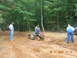 2005 Honda RANCHER - Three men in overalls are in a muddy wooded area with an all-terrain vehicle stuck in the mud.