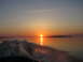 1996 Dodge 2500 - A boat leaves a foamy wake on calm water as the sun sets over a distant island.