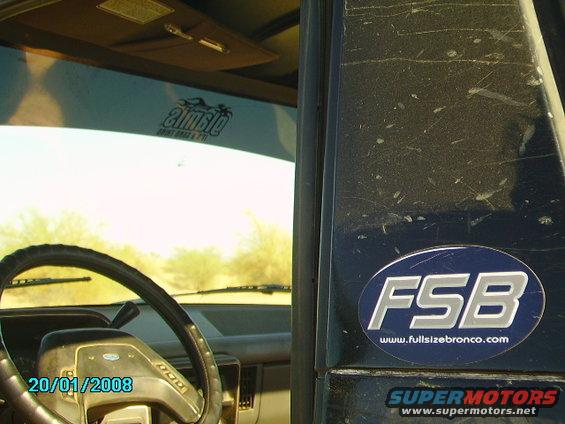 Inside of a dusty Ford Bronco with a steering wheel and an FSB sticker on the door