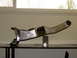 1996 Ford Bronco - A close-up view of a polished metal automotive suspension component, possibly a control arm, displayed indoors.