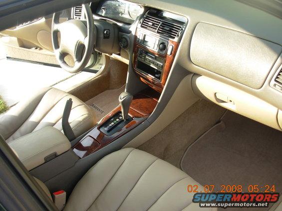Interior view of a car showing dashboard, steering wheel, center console with gear shifter, and seats. Floor mats have 'DIAMANTE' text