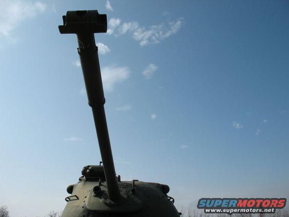 Tank turret and gun pointing up against a blue sky with clouds. Supermotors.net logo visible