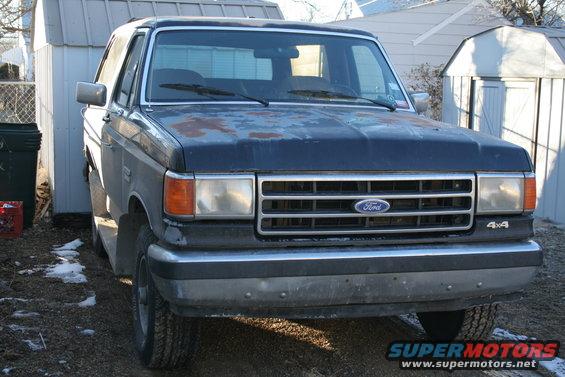 Ford Bronco with rust spots on hood, parked outside sheds