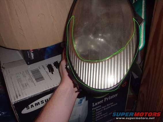 Headlight assembly with vertical fluting on the lower portion, held by a hand