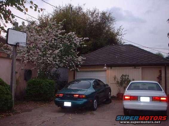 1996 Ford Taurus and white sedan parked in driveway near garage