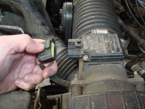 Hand disconnecting electrical connector from engine air intake sensor