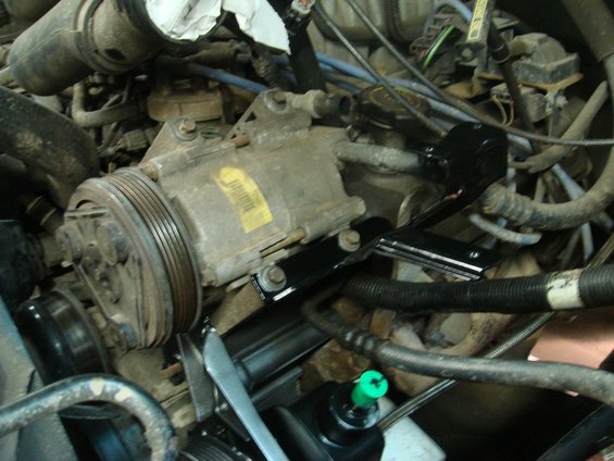 Air conditioning compressor in engine bay with yellow label
