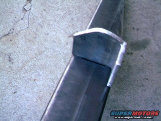 Close-up of a dark metal rear bumper section with a silver bracket attached
