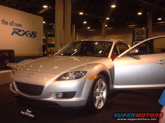 Silver Mazda RX-8 with driver door open, RX-8 badging visible on wall behind