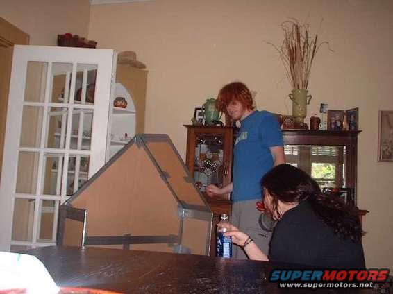Cardboard structure on a table with two people in a room