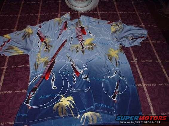 Hawaiian shirt with guitars and palm trees on a bed