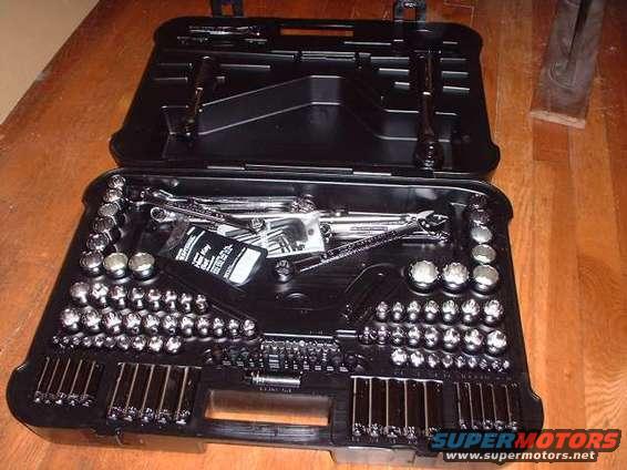 Open black tool case with sockets, wrenches, and other tools neatly arranged inside