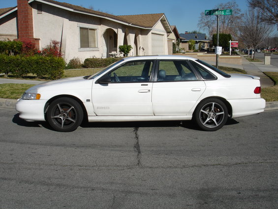 Side view of a white 1991 Ford Taurus parked on a residential street