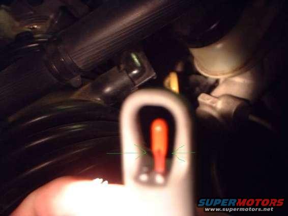Close-up of engine bay with focus on a red indicator light and hoses