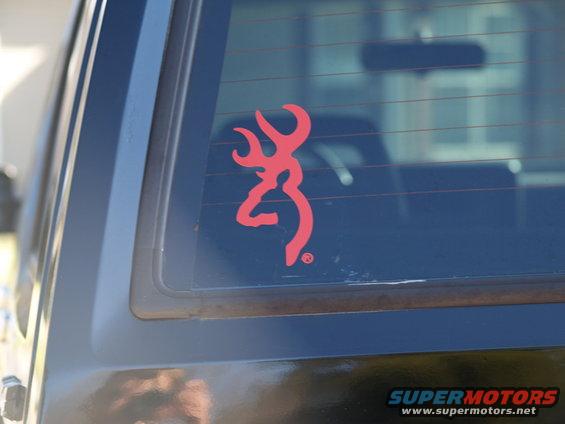 Back window of a dark SUV with a red Browning deer logo sticker. Supermotors.net watermark at bottom right
