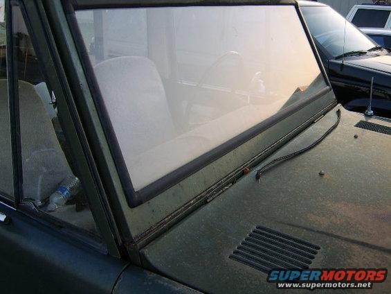 Interior view of a green vehicle's dashboard and seats, with another vehicle visible outside