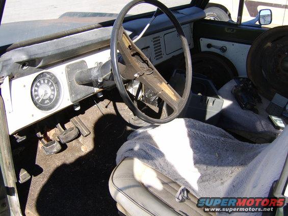 Interior view of a vintage vehicle with a large steering wheel and dashboard gauges