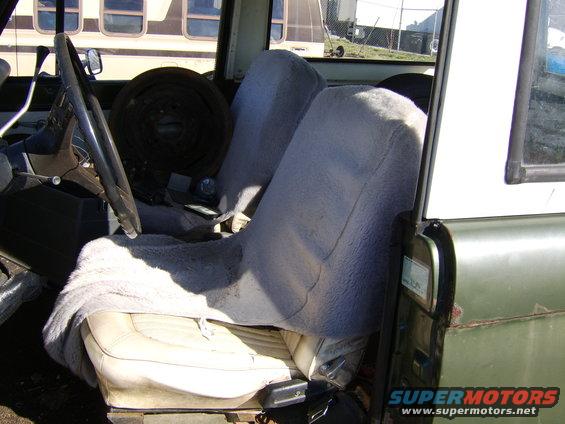 Interior view of a vehicle with two front seats covered in fuzzy grey material. Steering wheel and dashboard visible