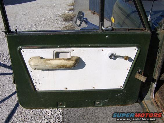 Door panel with armrest, window crank, and door handle. Exterior shows dark green paint